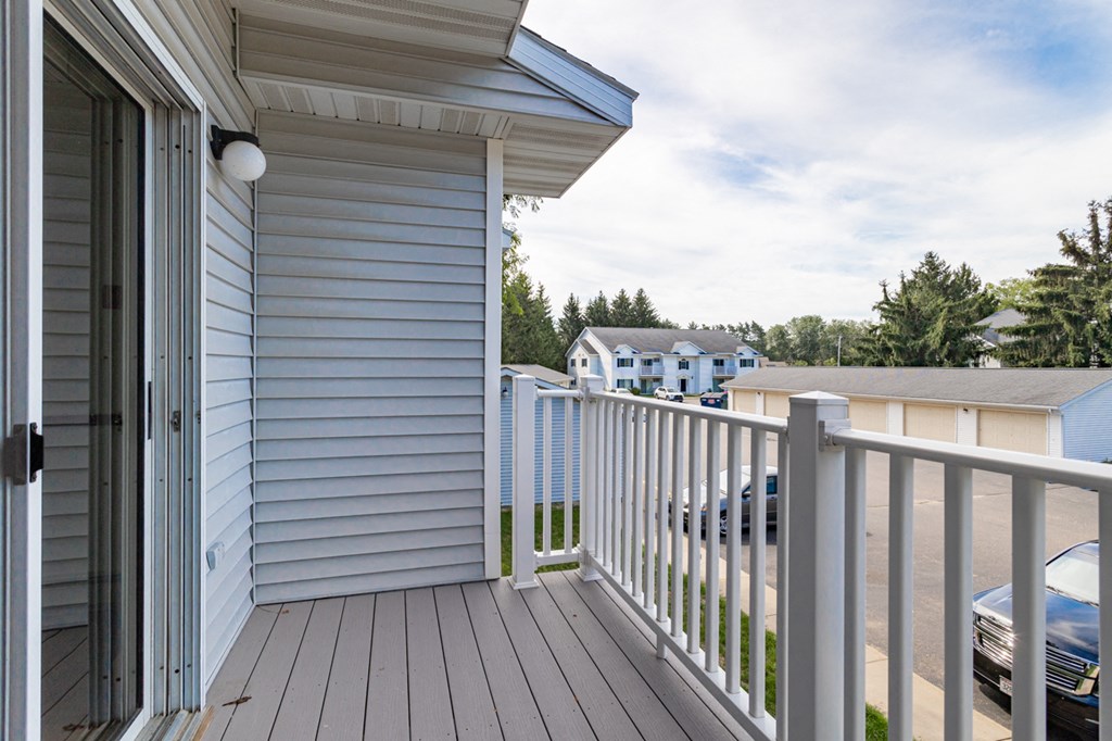 a balcony with a view of a house and a parking lot