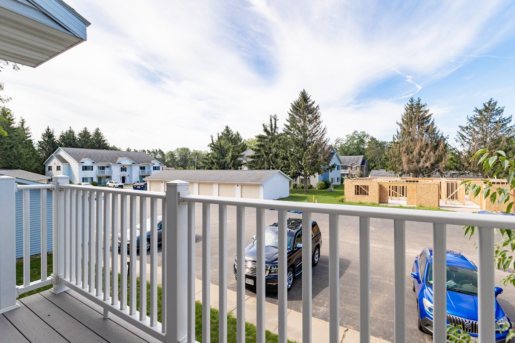 the view from the deck of a house with cars parked in a parking lot