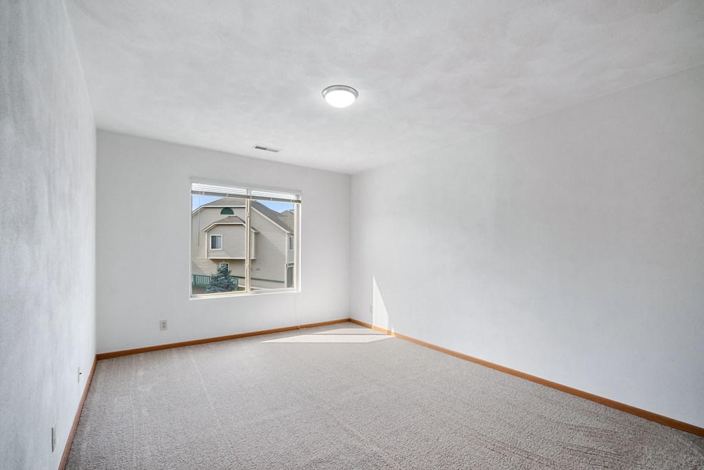 a room with white walls and a window and a carpet