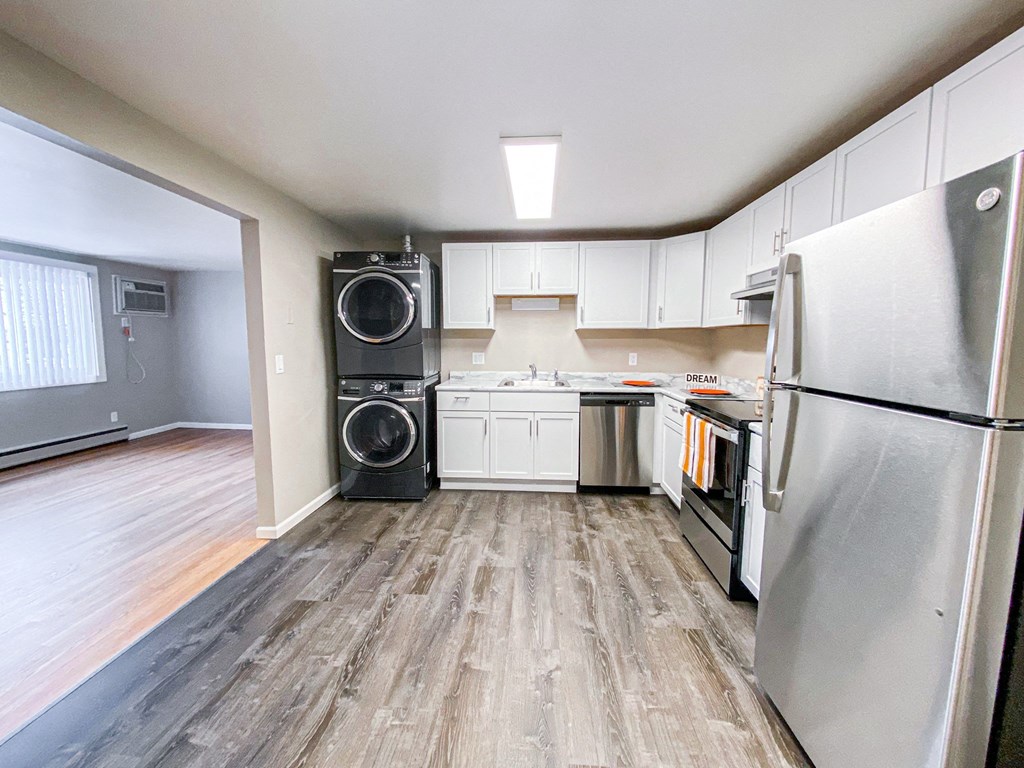 a kitchen with white cabinets and stainless steel appliances and a washer and dryer