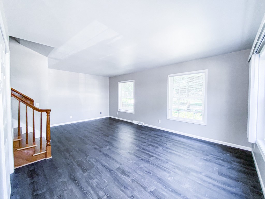 A room with a wooden staircase and grey flooring.