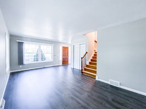 A spacious room with a staircase leading to the second floor.