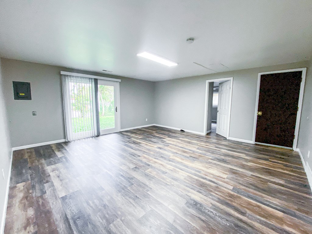 an empty living room with wooden floors and a sliding glass door
