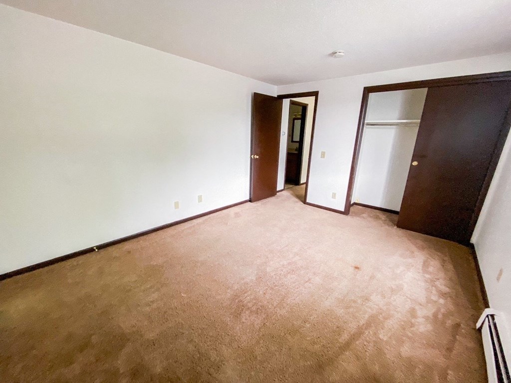 an empty living room with a wooden floor and a door to a closet