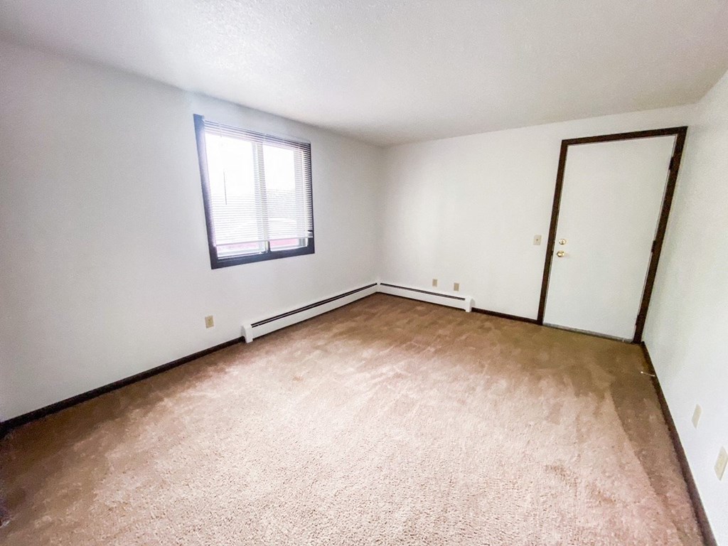 an empty living room with white walls and a window