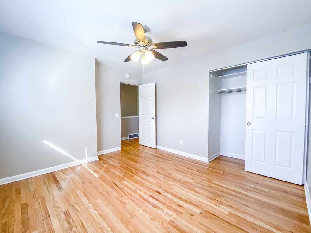 an empty living room with wood floors and a ceiling fan