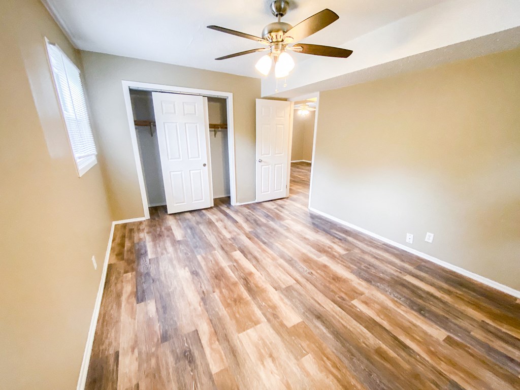 an empty living room with wood floors and a ceiling fan