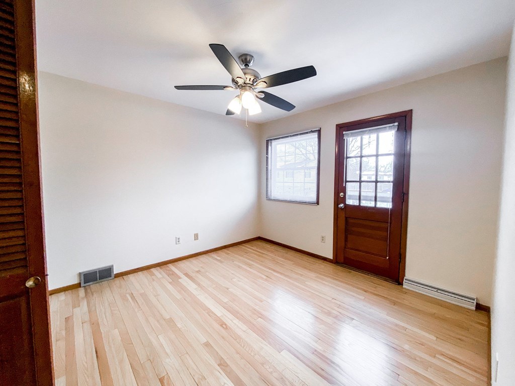 an empty living room with wooden floors and a ceiling fan