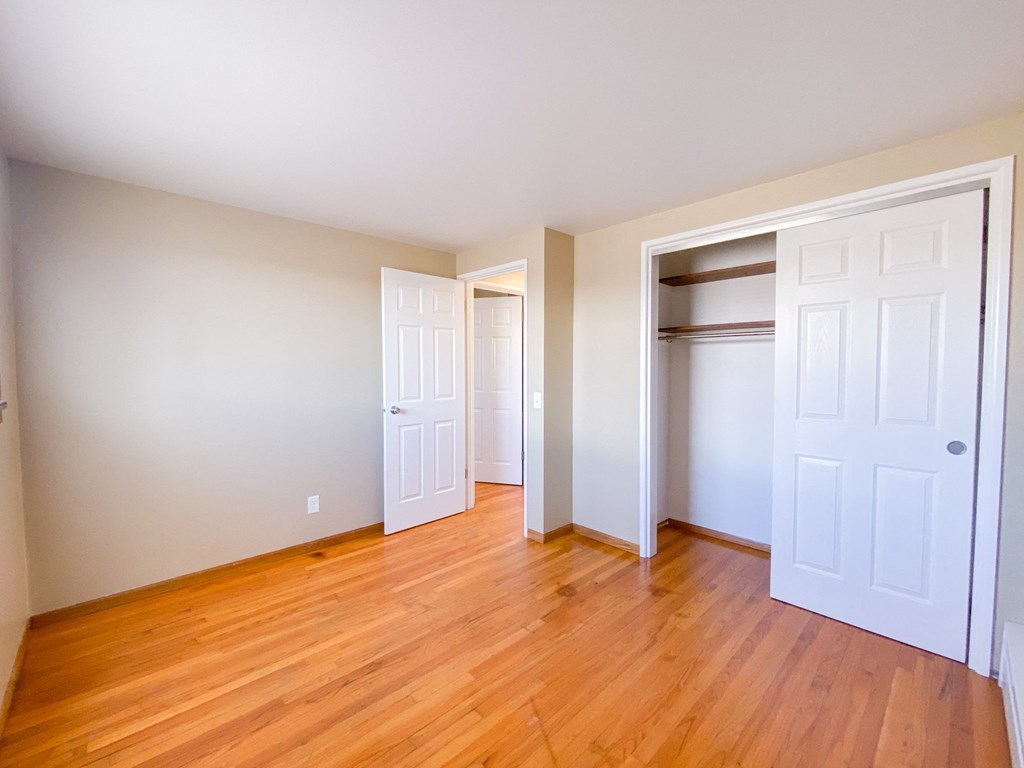 an empty room with wooden floors and white closets