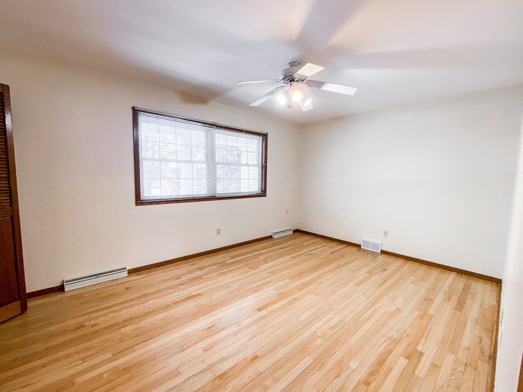 an empty living room with wood floors and a ceiling fan