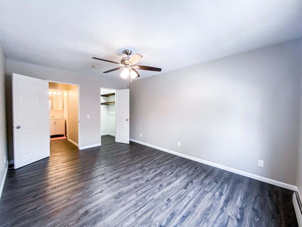 an empty living room with wood flooring and a ceiling fan