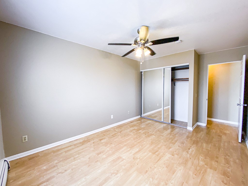 an empty living room with wood floors and a ceiling fan
