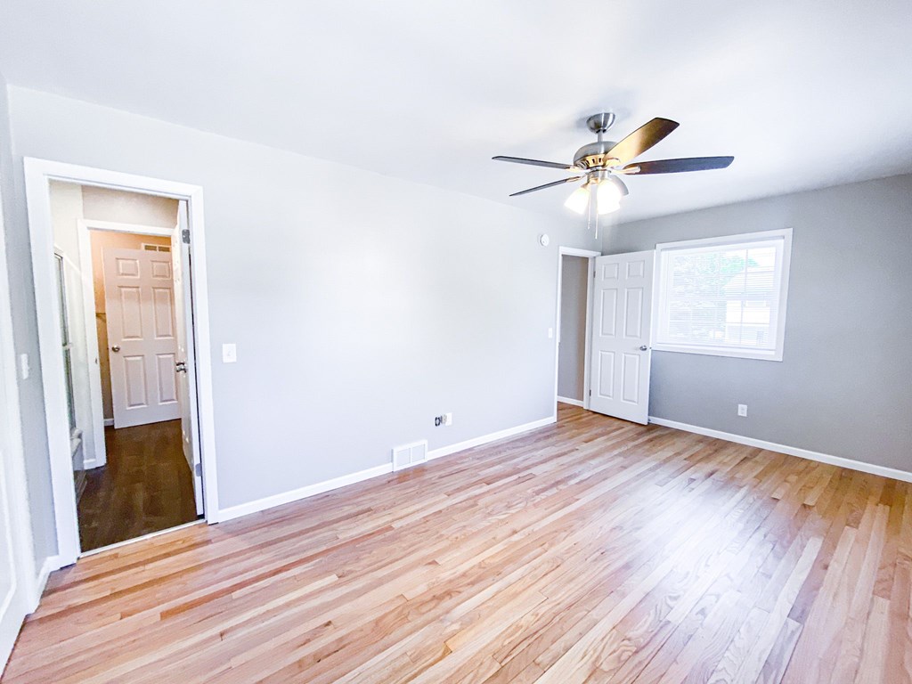 A room with a ceiling fan and wooden flooring.