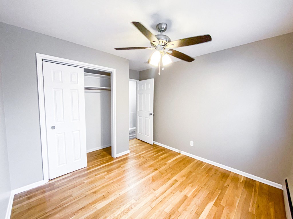 an empty living room with wood floors and a ceiling fan