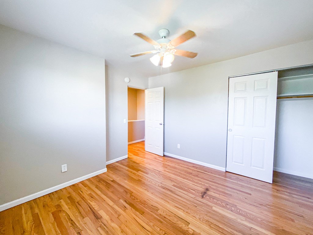 an empty living room with wood floors and a ceiling fan