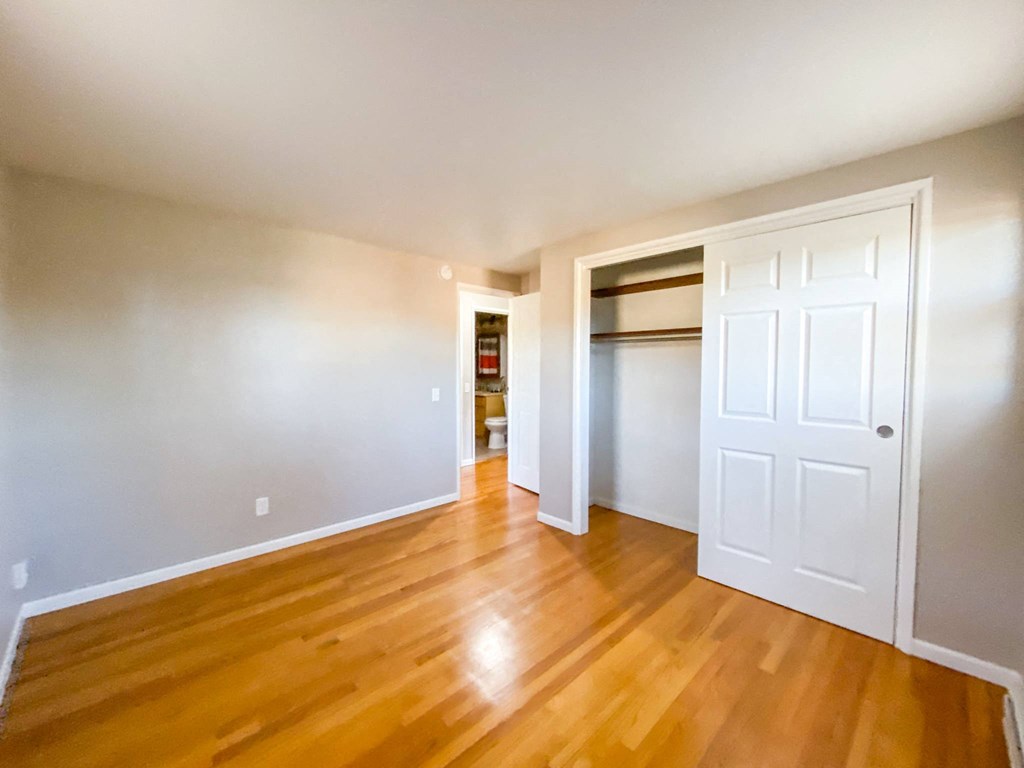 an empty living room with wooden floors and a white door