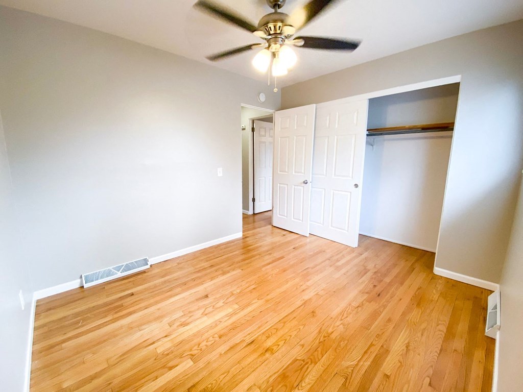 an empty living room with wood floors and a ceiling fan