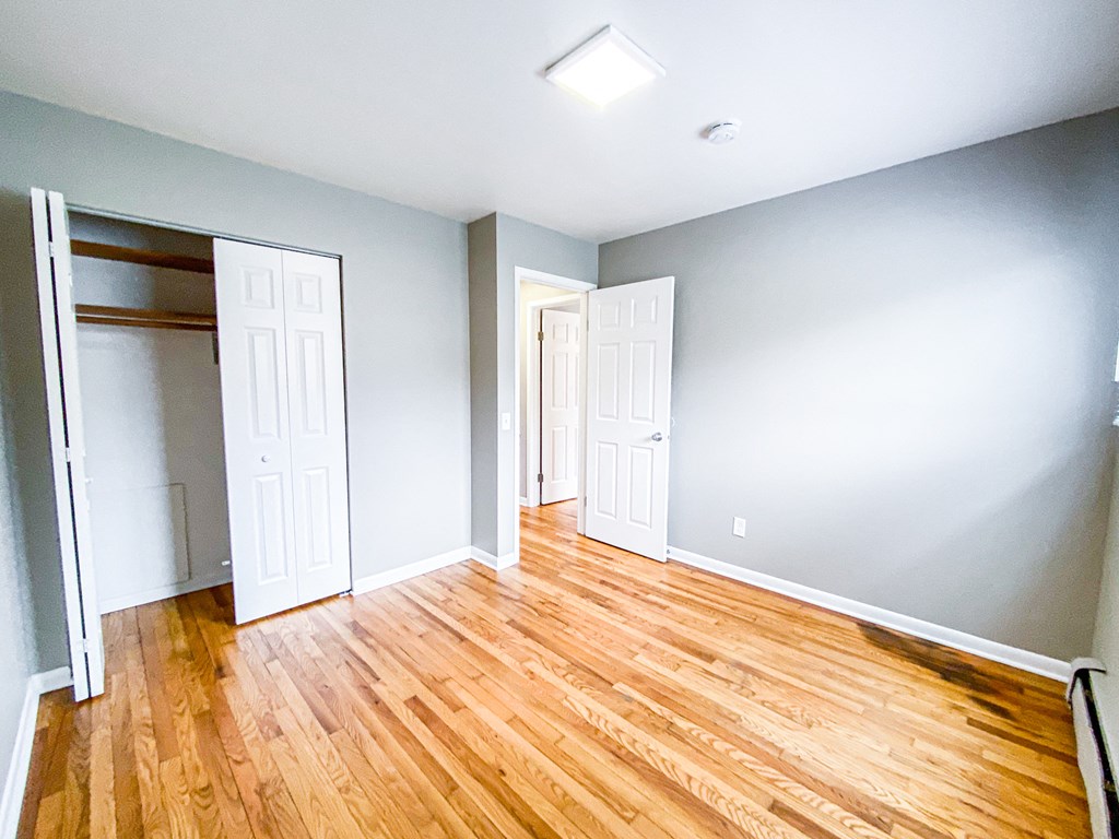an empty room with wood floors and a closet
