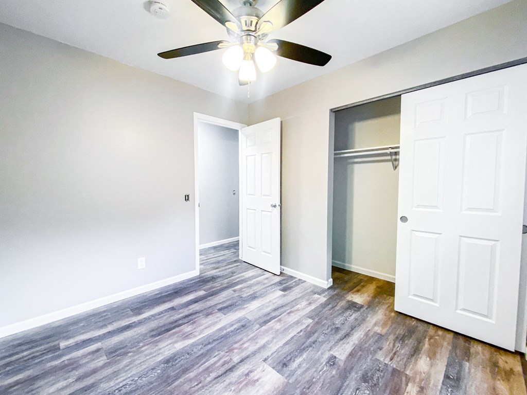 an empty room with a ceiling fan and a closet