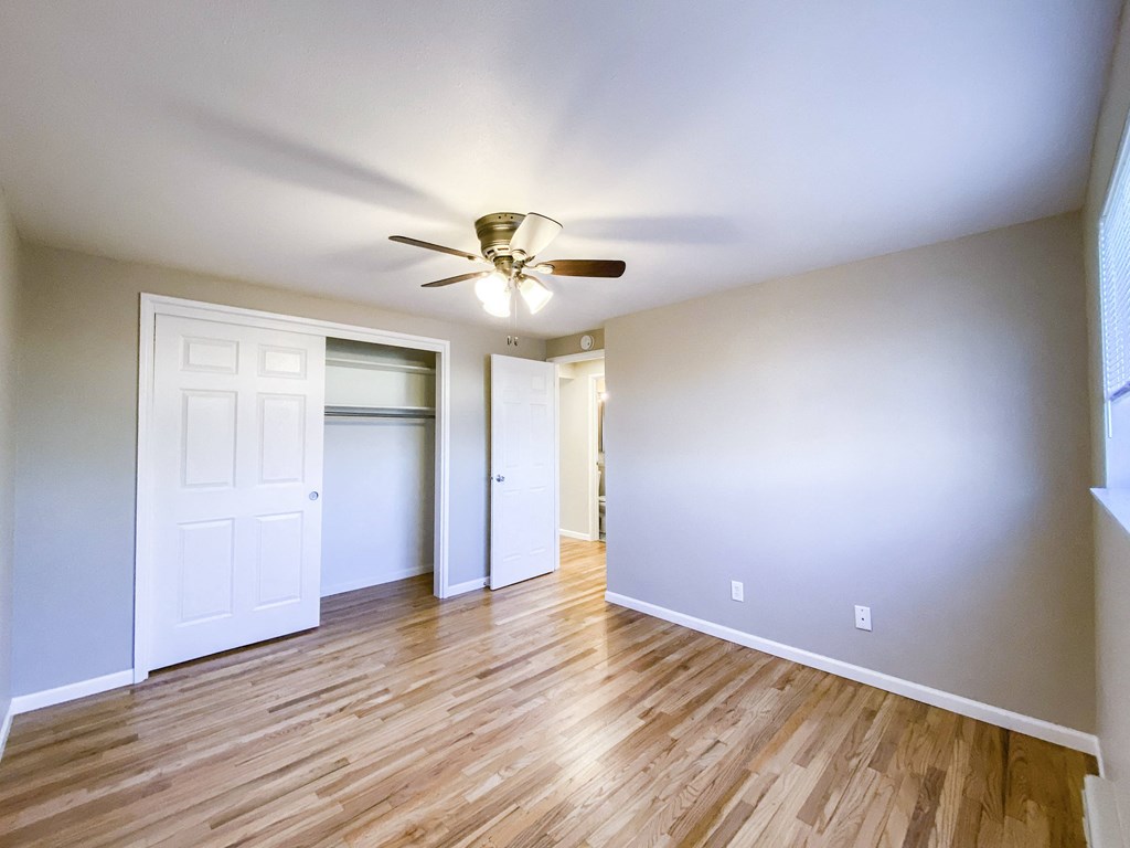 an empty living room with wood floors and a ceiling fan
