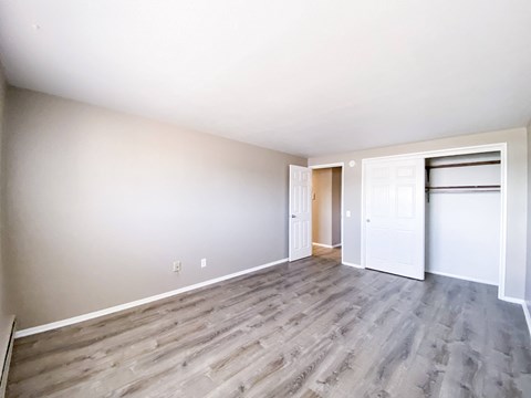 an empty living room with wood flooring and a door to a closet