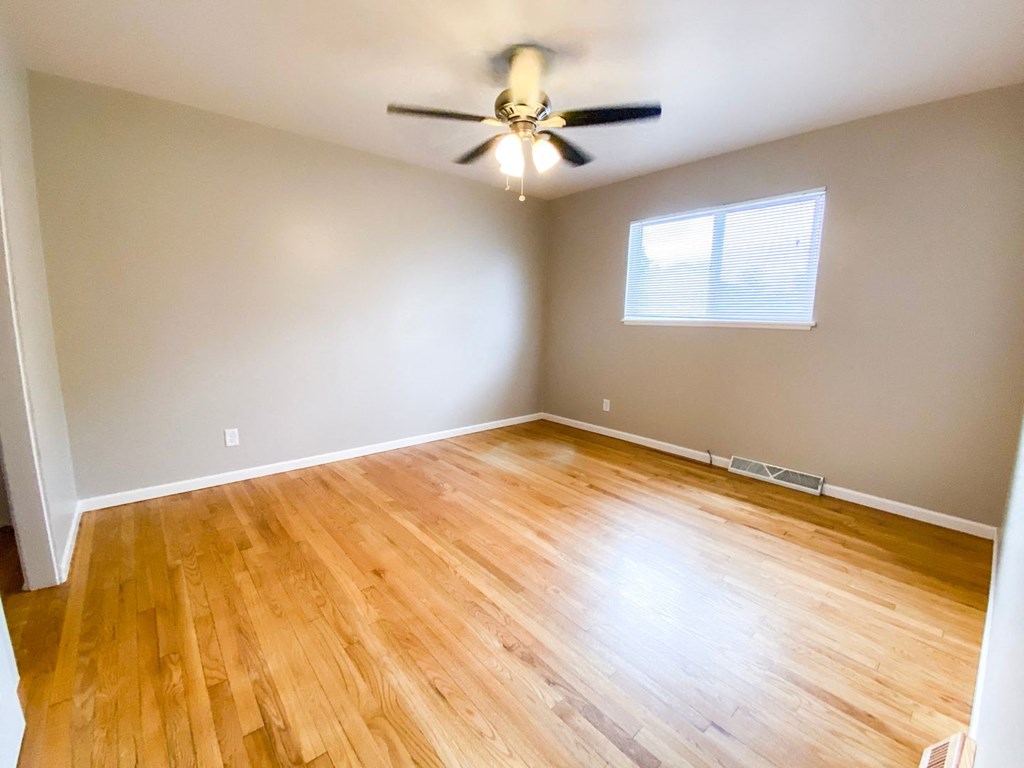 an empty living room with wooden floors and a ceiling fan