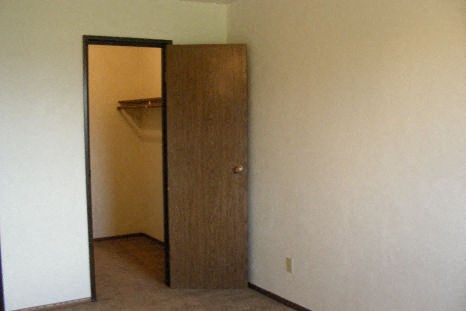 an empty room with a door to a closet and a mirror