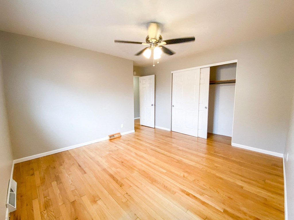 an empty living room with wood floors and a ceiling fan
