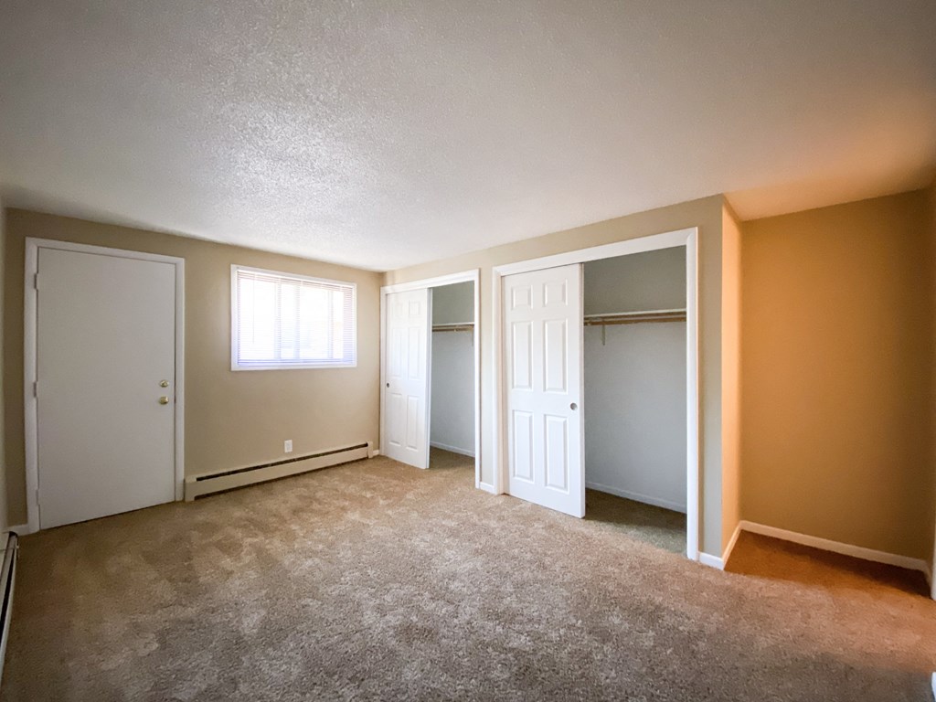 an empty living room with a closet and a window