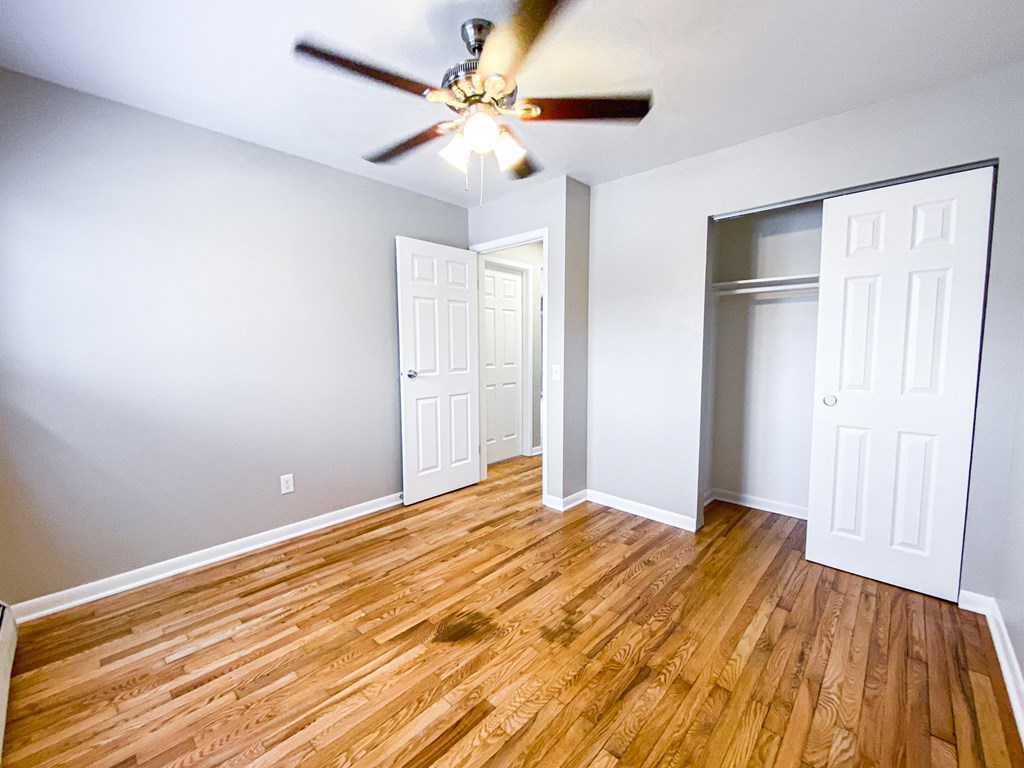 an empty living room with wood floors and a ceiling fan