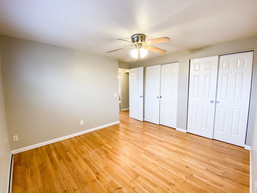 an empty living room with wood floors and a ceiling fan