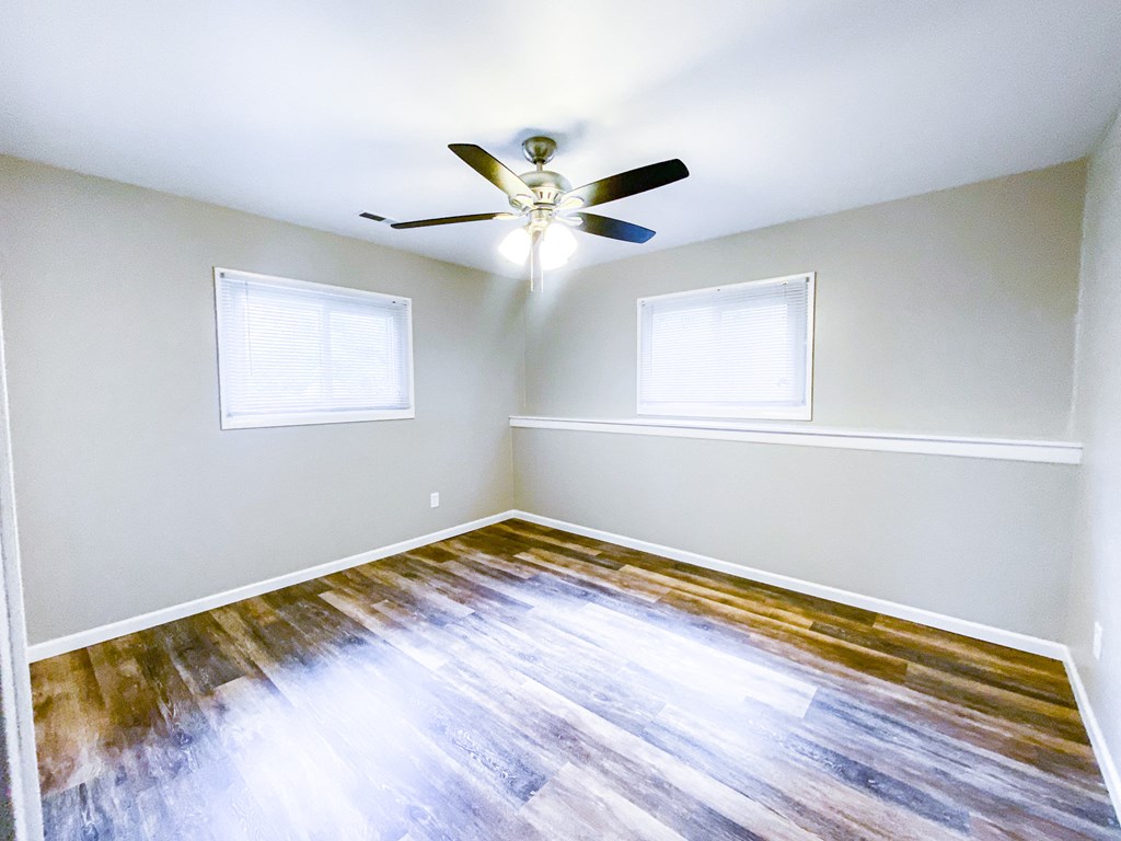 an empty room with a ceiling fan and two windows