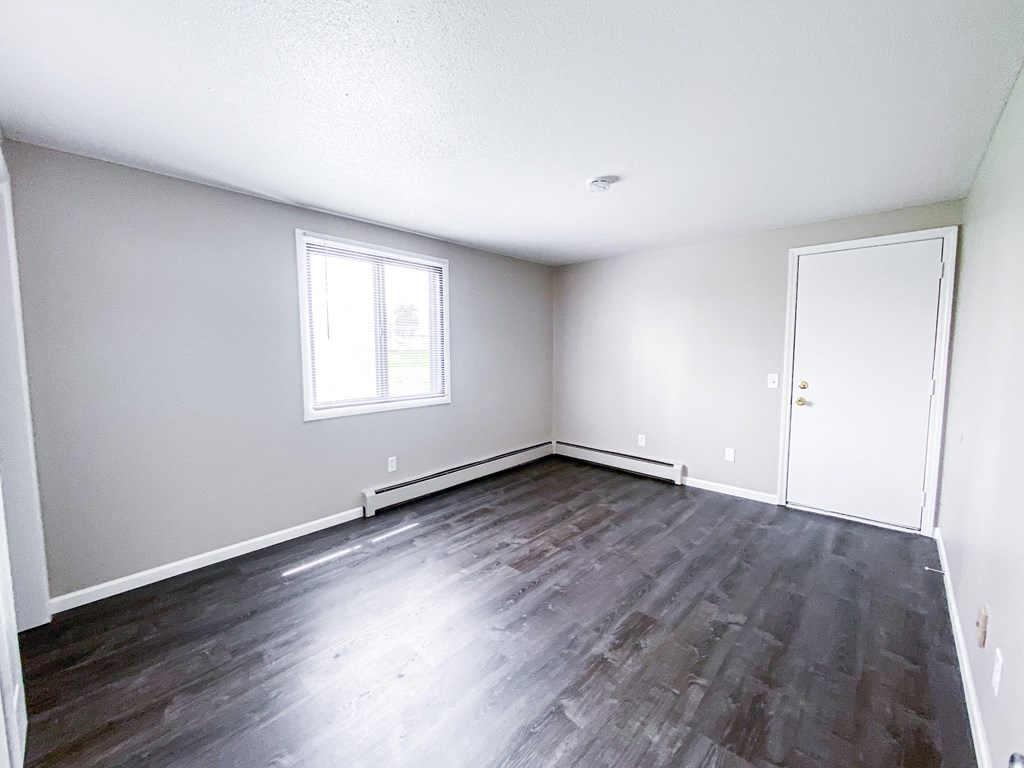 an empty living room with white walls and wood floors