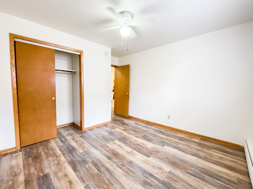 an empty living room with wood flooring and a door to a closet