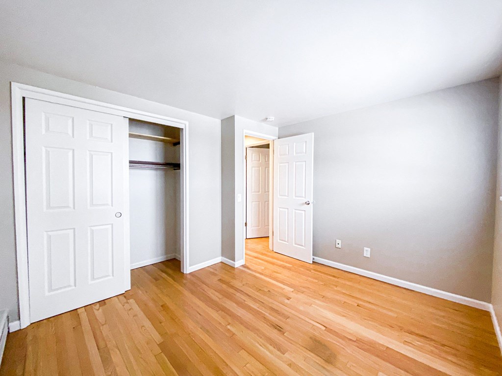 an empty room with wooden floors and white closets