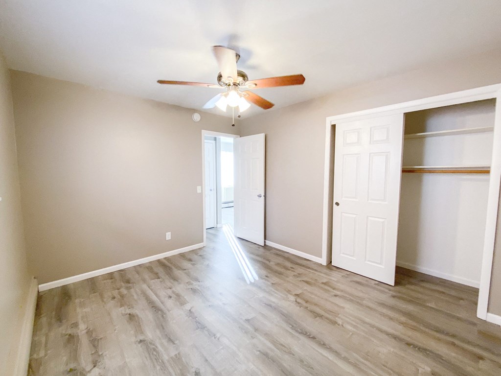 an empty living room with a ceiling fan and a closet