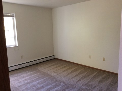 A room with a carpeted floor and a window.