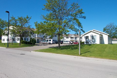 A street view of a residential area with houses and parked cars.