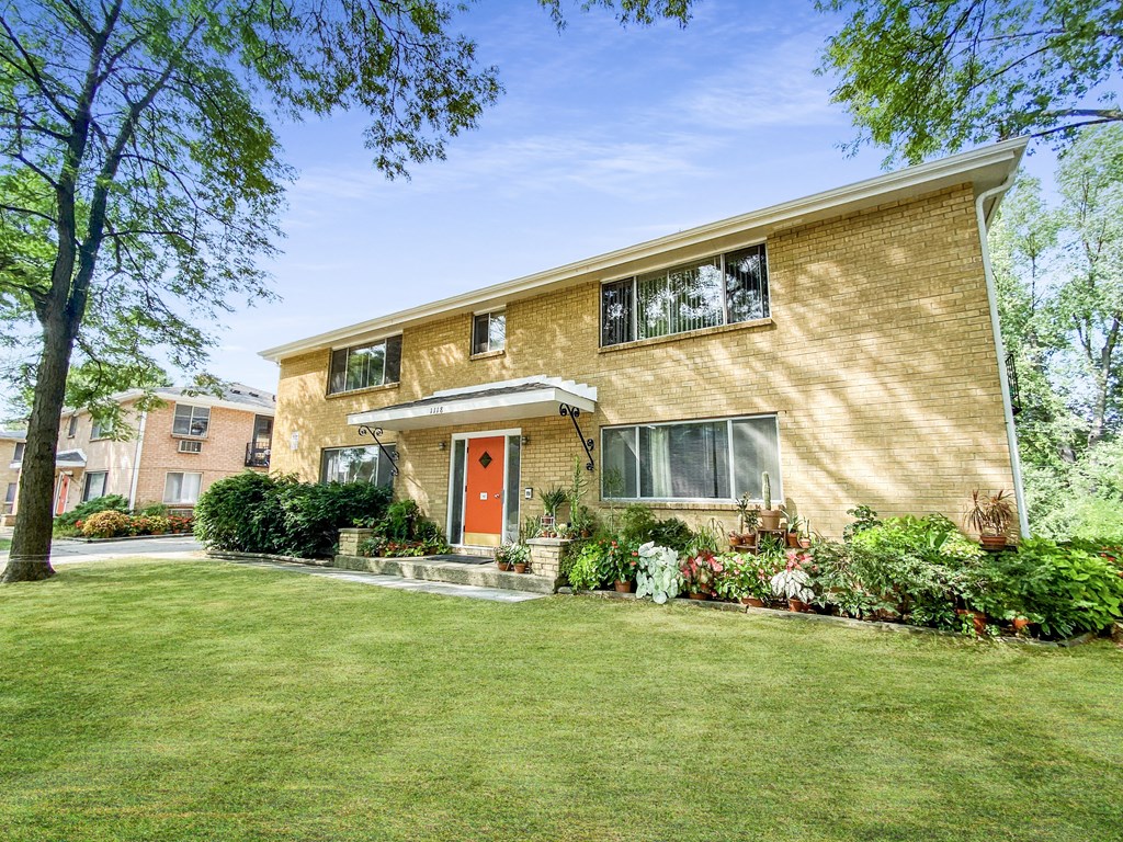 the front of a brick house with a red door
