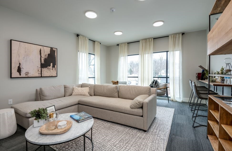 A living room with a large beige sofa, a coffee table, and a painting on the wall.