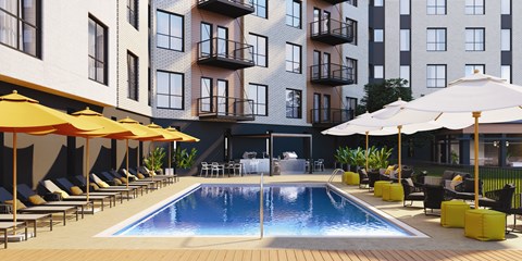 A pool surrounded by lounge chairs and umbrellas in front of a building.