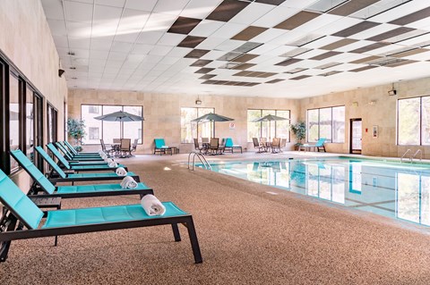 A large indoor swimming pool with lounge chairs and umbrellas.