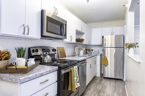 A modern kitchen with white cabinets and stainless steel appliances.