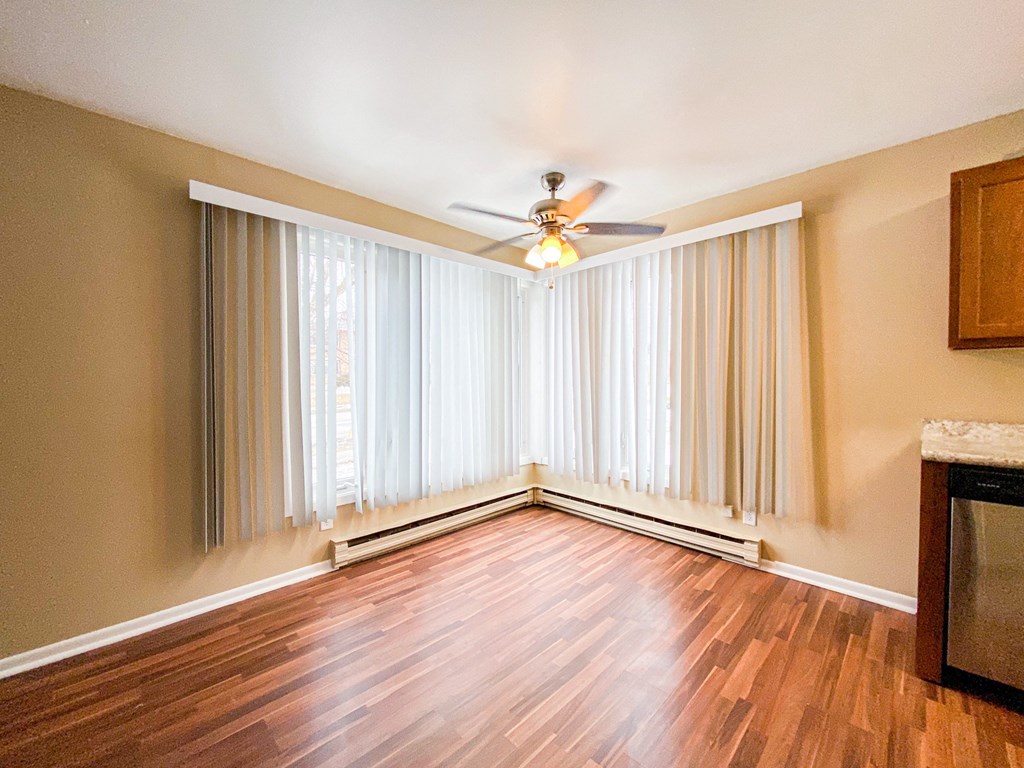 an empty living room with curtains and a ceiling fan