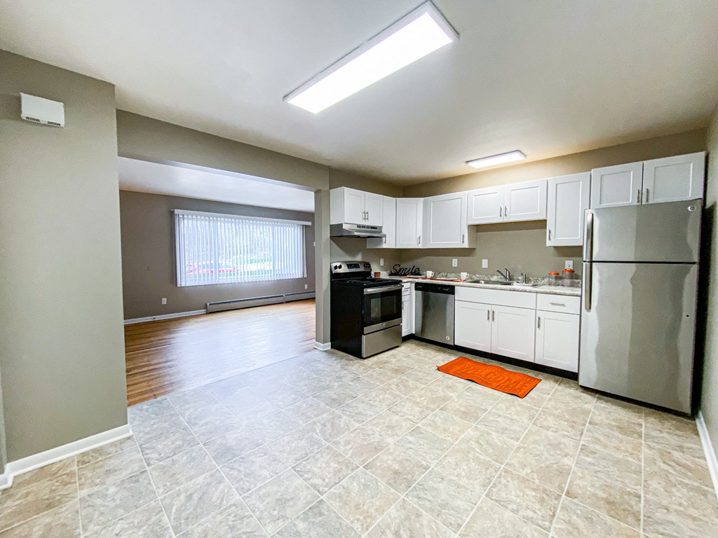 an empty kitchen with white cabinets and stainless steel appliances