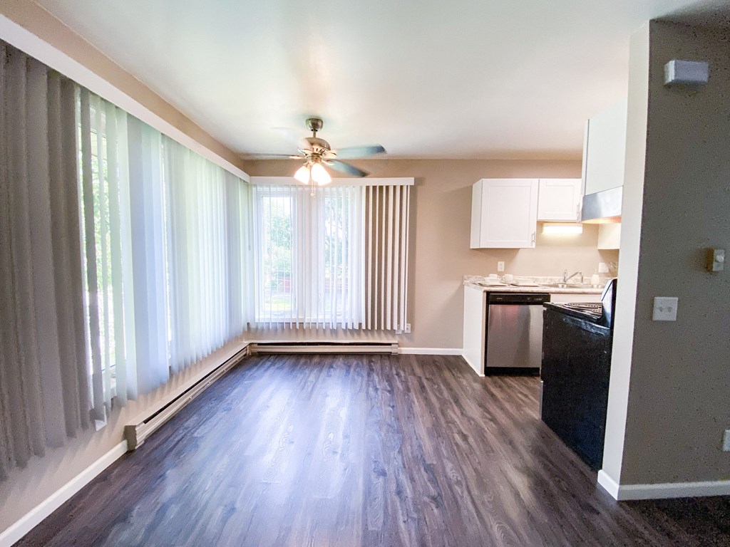 an empty living room with a large window and a ceiling fan