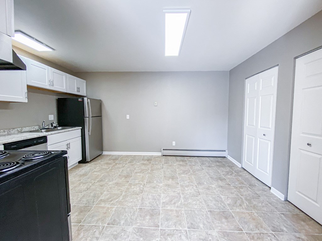 an empty kitchen and living room with a stove and refrigerator