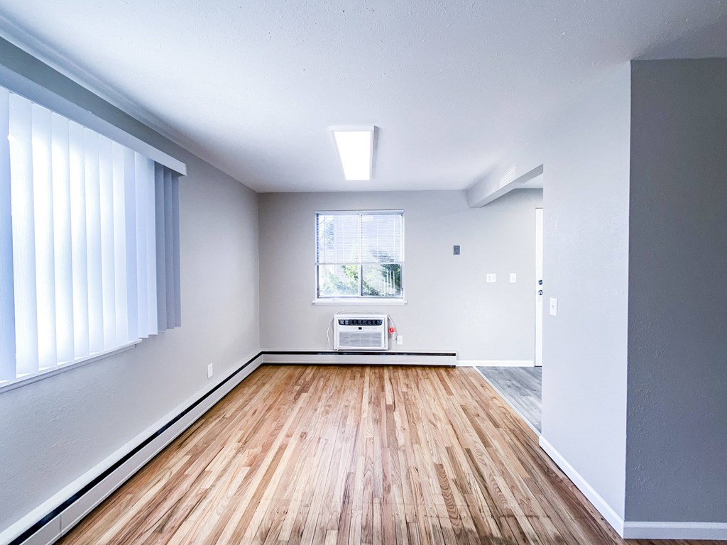 an empty living room with wood floors and a window