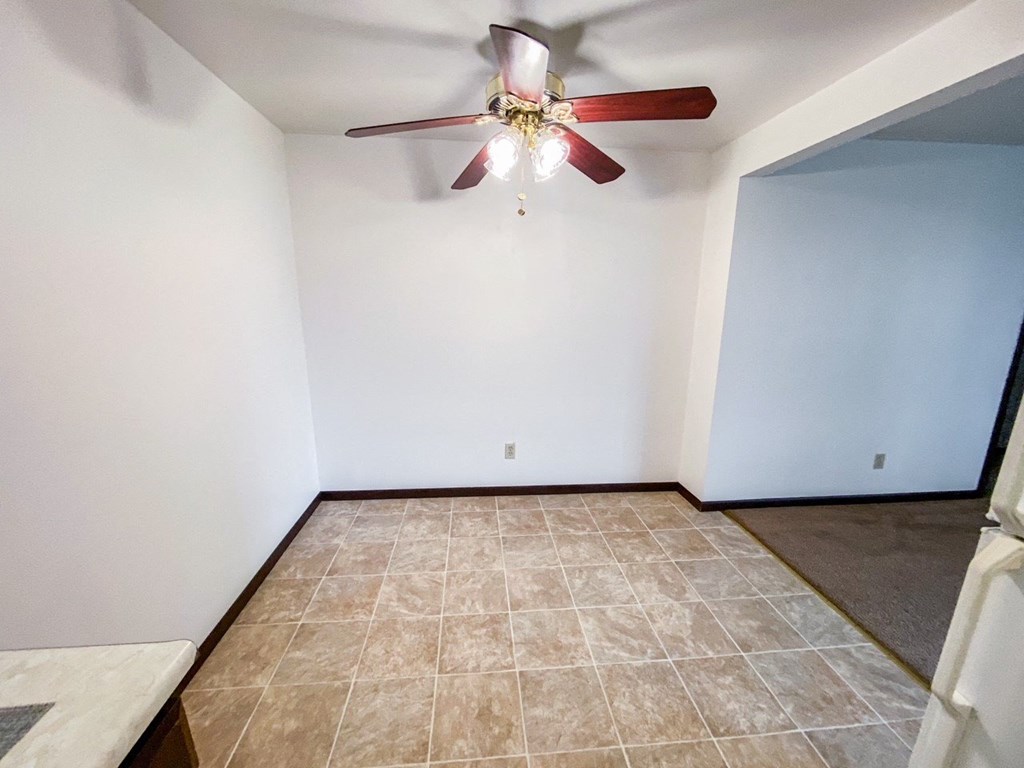an empty living room with a ceiling fan