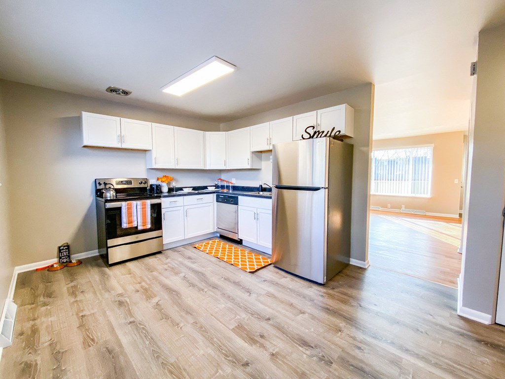 an empty kitchen with stainless steel appliances and white cabinets
